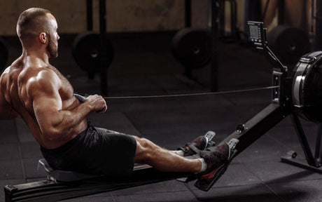 Was wird auf einem rudergeraet trainiert - Mann trainiert intensiv auf Indoor Rower